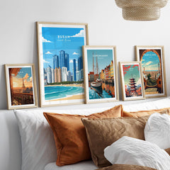 Set of five framed travel posters of world cities above a bed with neutral pillows.