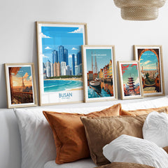 Framed travel posters of Paris, Busan, Copenhagen, Tokyo, and Barcelona above a bed.