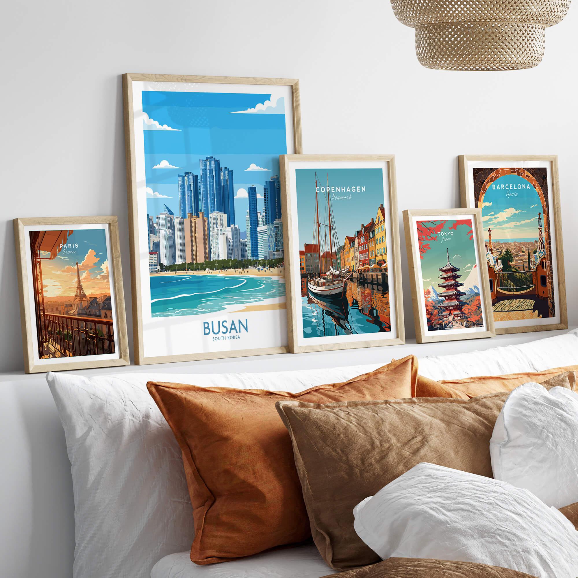 Framed travel posters of Paris, Busan, Copenhagen, Tokyo, and Barcelona above a bed.