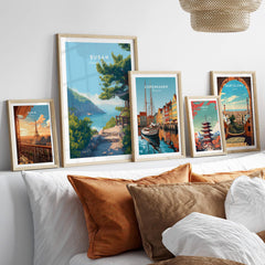 Five framed travel posters featuring Paris, Busan, Copenhagen, Tokyo, and Barcelona above a bed