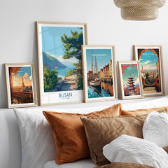 Framed travel posters of Paris, Busan, Copenhagen, Tokyo, and Barcelona above a bed
