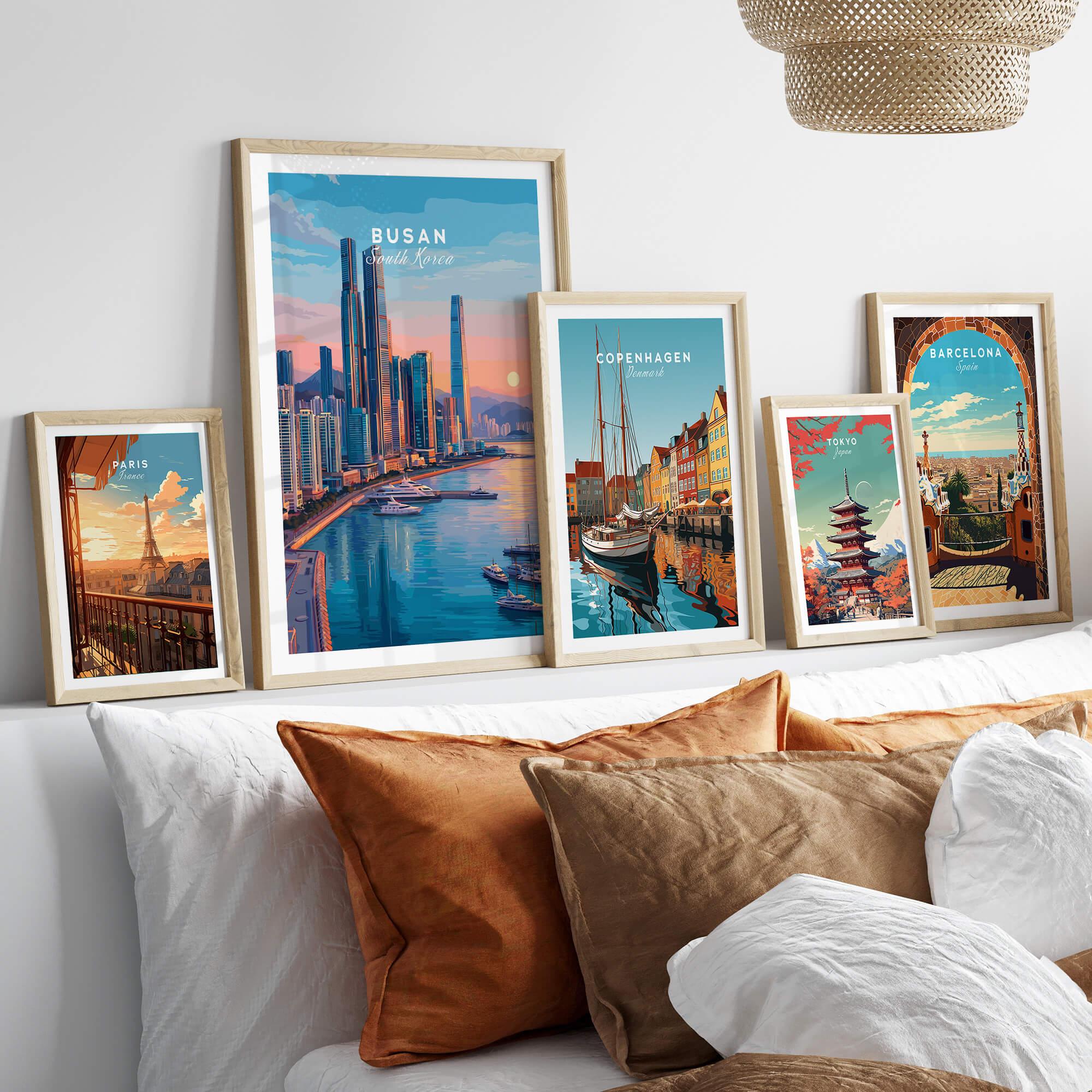 Five framed travel art prints of Paris, Busan, Copenhagen, Tokyo, and Barcelona above a bed