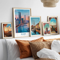 Set of five framed travel art prints above bed, featuring city skylines and landmarks