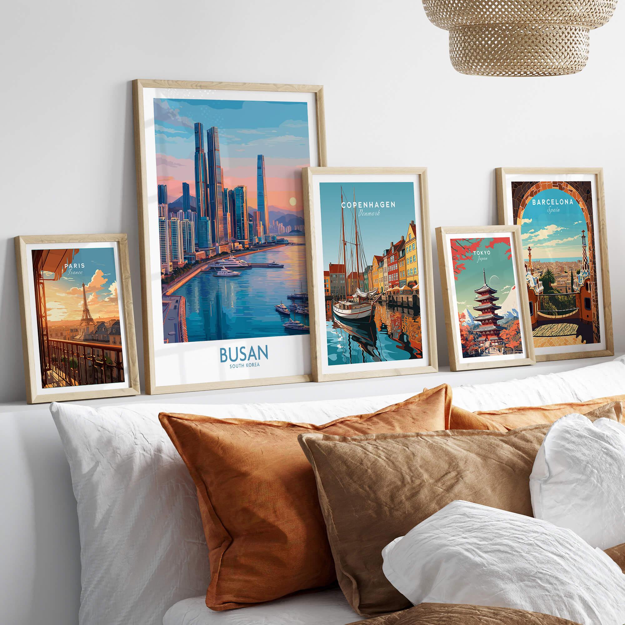Set of five framed travel art prints above bed, featuring city skylines and landmarks
