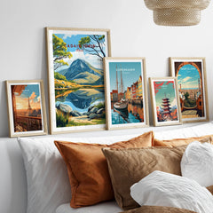 Five framed travel and city posters above a bed, featuring Paris, Copenhagen, Tokyo, Barcelona, and a mountain landscape.