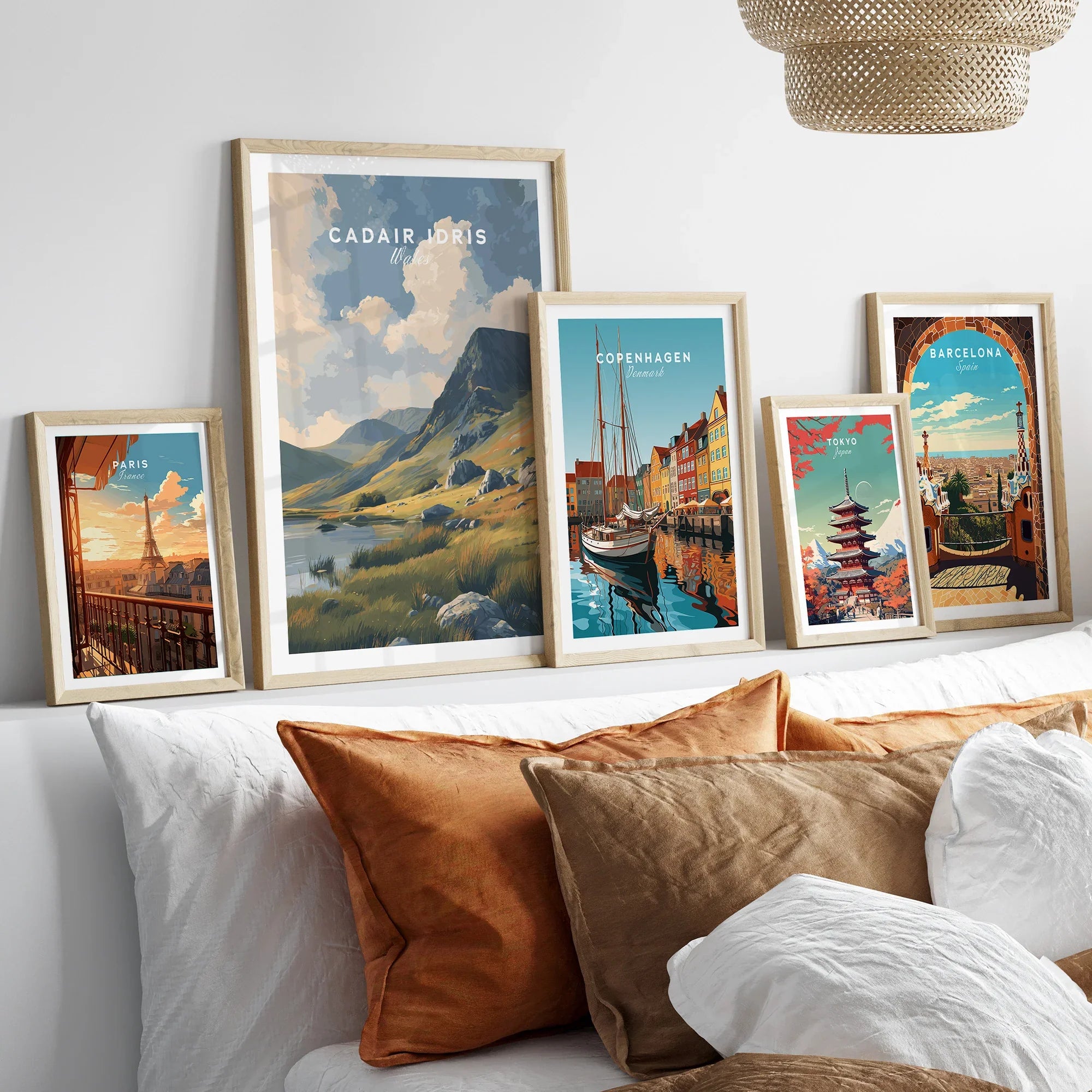 Set of five framed travel art prints above bed, featuring city and landscape posters