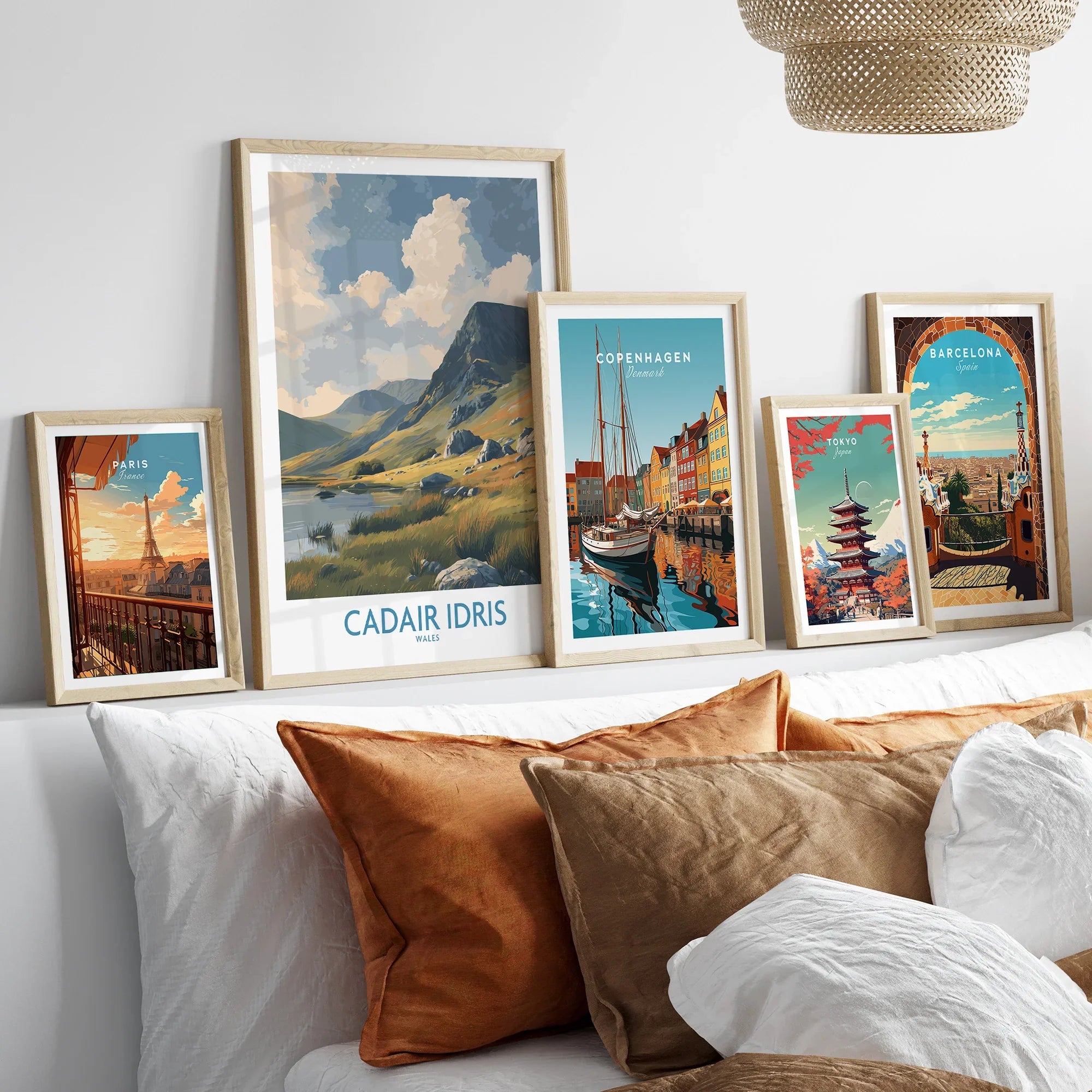 Framed travel posters of Paris, Wales, Copenhagen, Tokyo, and Barcelona above a bed