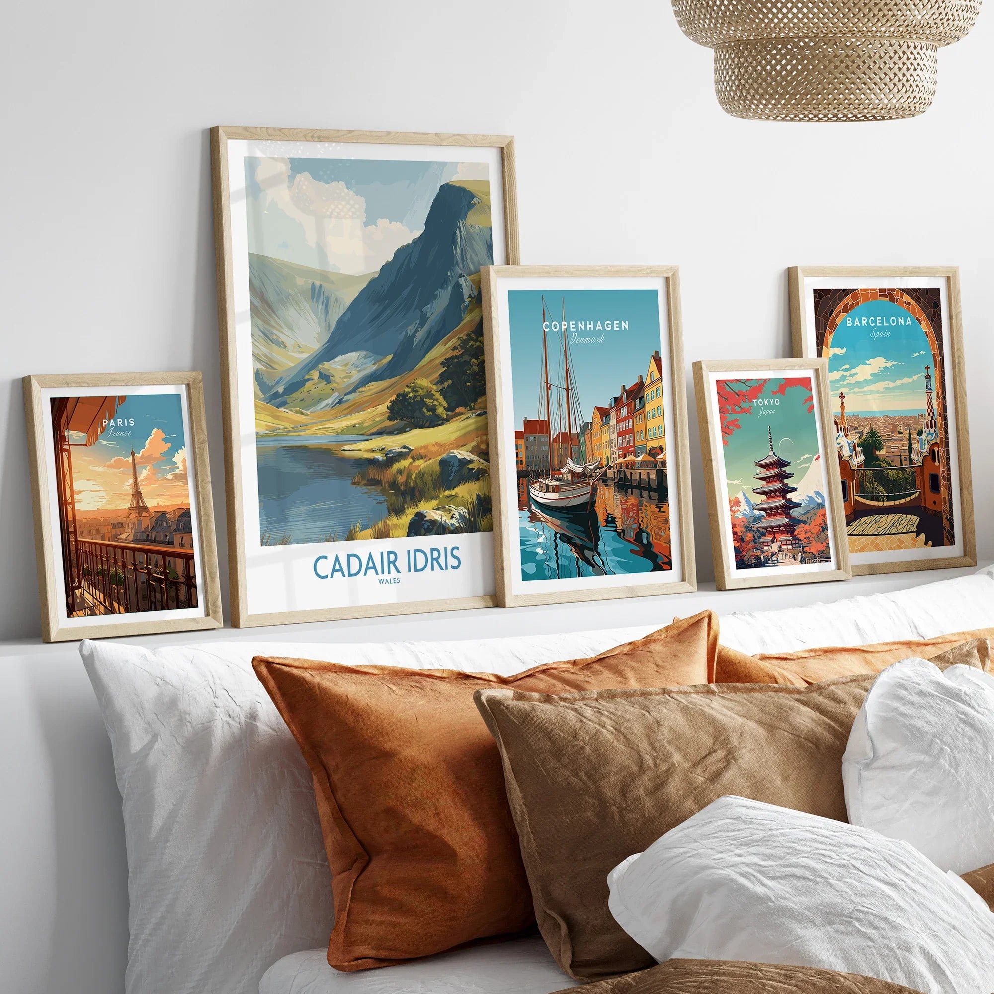Framed travel posters of Paris, Cadair Idris, Copenhagen, Tokyo, and Barcelona above a bed.