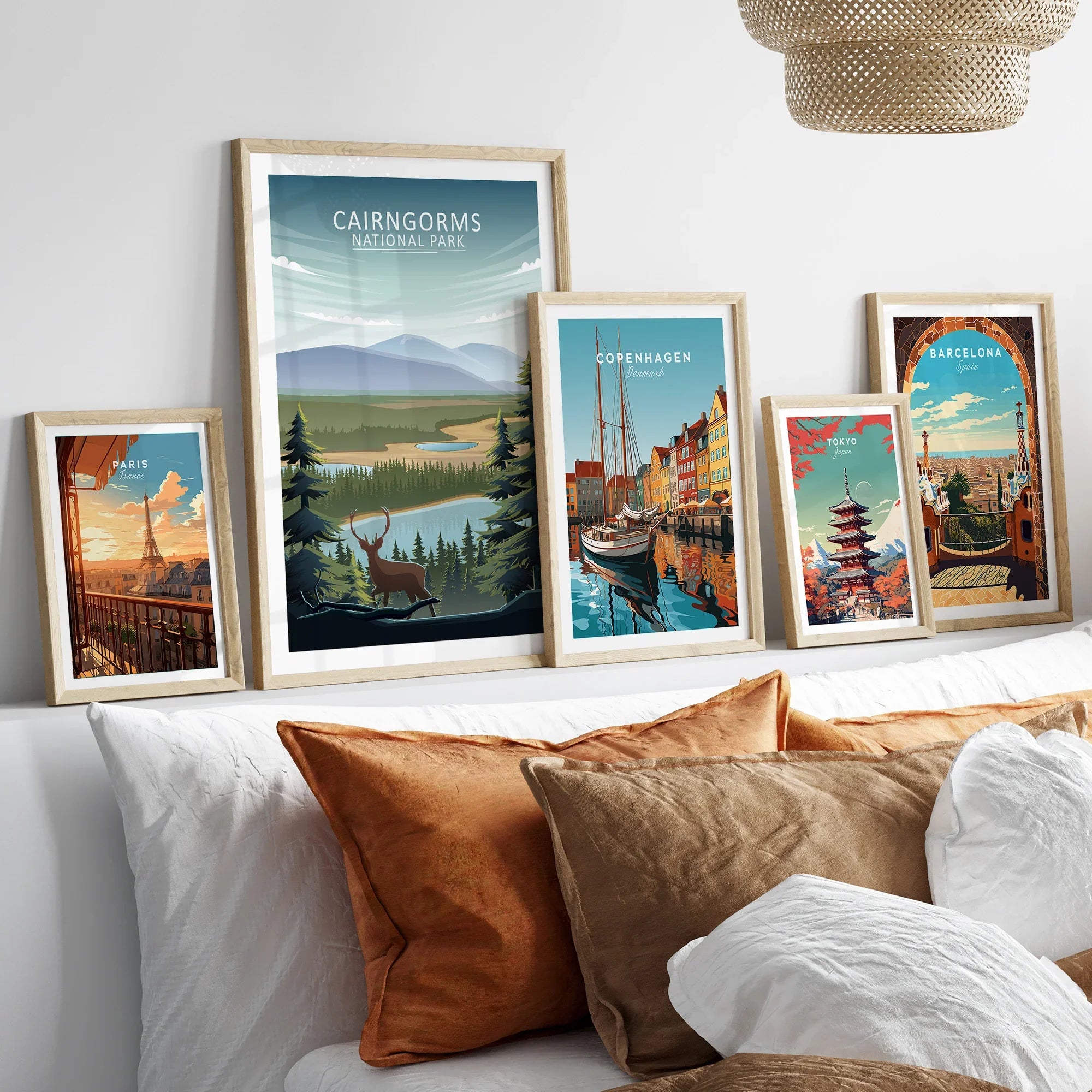 Set of five framed travel posters above a bed, featuring Paris, Cairngorms, Copenhagen, Tokyo, and Barcelona.