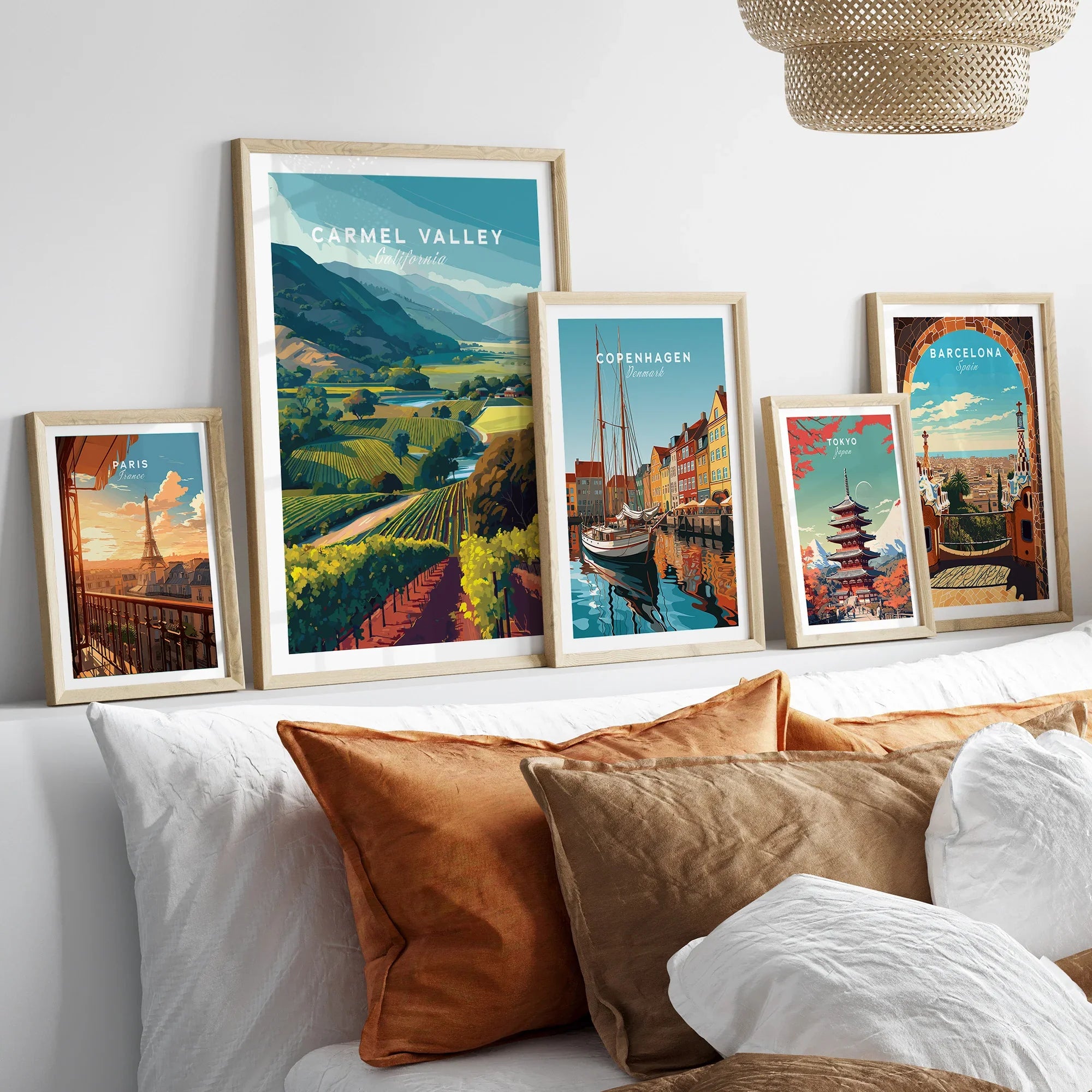 Set of five framed travel art prints above bed, featuring Paris, Carmel Valley, Copenhagen, Tokyo, Barcelona.