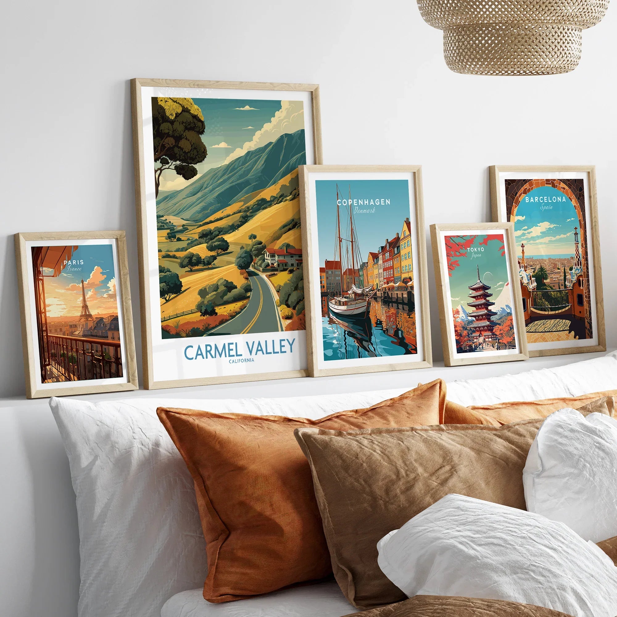 Set of five framed travel posters above a bed, featuring Paris, Carmel Valley, Copenhagen, Tokyo, and Barcelona.