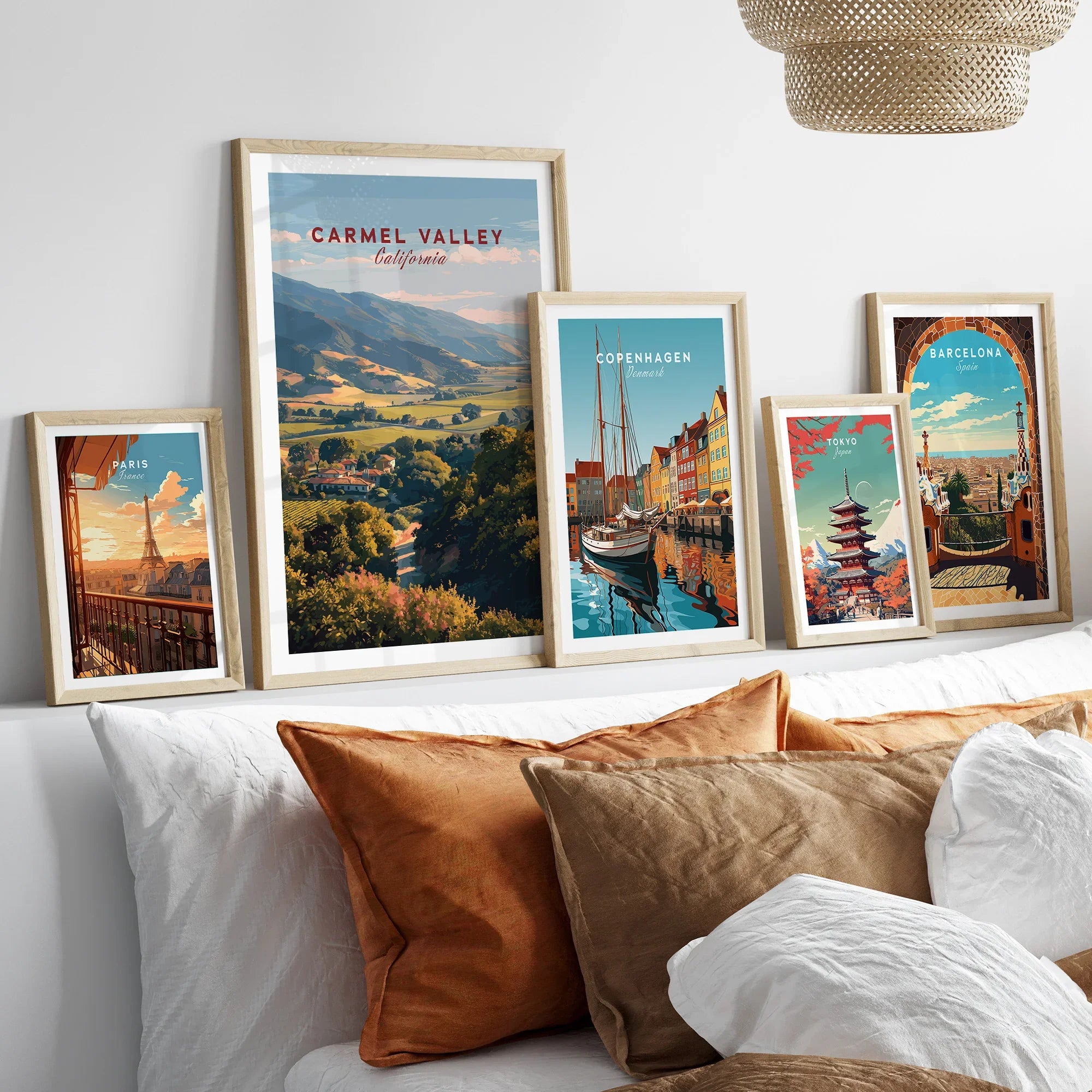 Set of five framed travel posters above bed, featuring Paris, Carmel Valley, Copenhagen, Tokyo, and Barcelona wall art prints in natural wood frames.