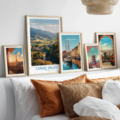 Five framed travel art prints of world cities displayed above a bed with neutral pillows.