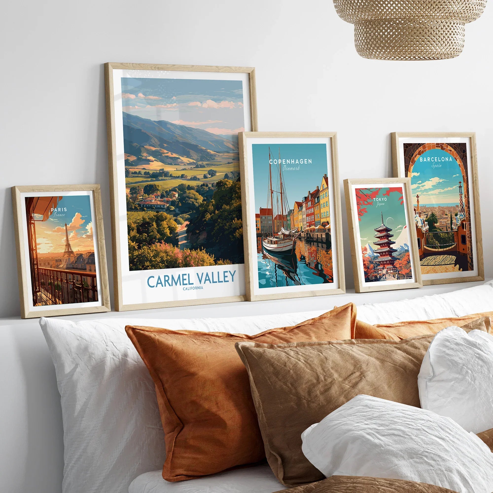 Five framed travel art prints of world cities displayed above a bed with neutral pillows.