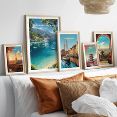 Set of five framed travel posters above bed, featuring Catalina Island, Paris, Copenhagen, Tokyo, and Barcelona wall art.