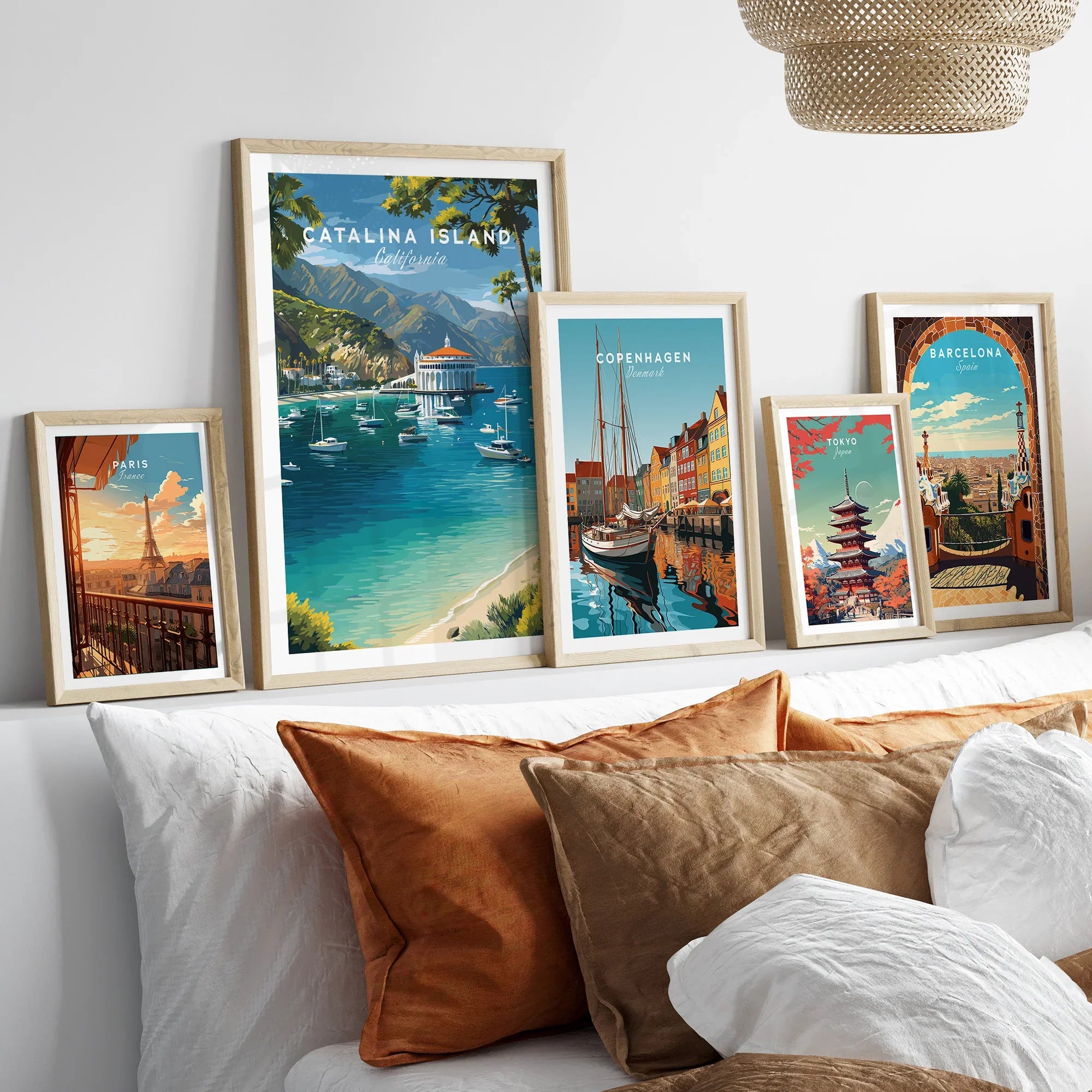 Set of five framed travel posters above bed, featuring Catalina Island, Paris, Copenhagen, Tokyo, and Barcelona wall art.