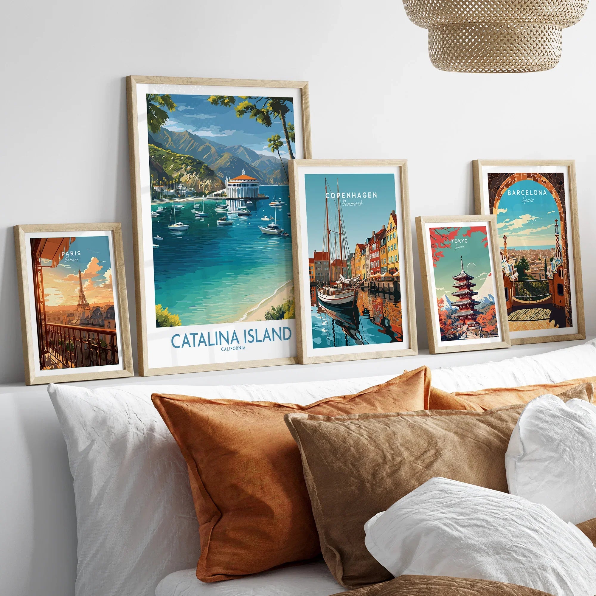 Framed travel posters above a bed featuring Catalina Island, Paris, Copenhagen, Tokyo, and Barcelona.