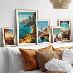 Set of five framed travel posters above bed, featuring Catalina Island, Paris, Copenhagen, Tokyo, Barcelona with natural wood frames.