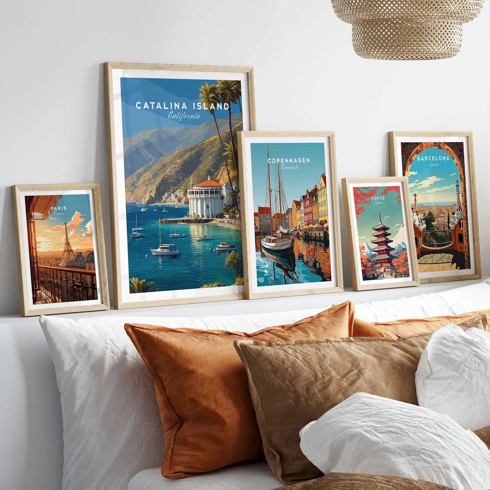 Framed travel poster art prints of Catalina Island, Paris, Copenhagen, Tokyo, and Barcelona above bed