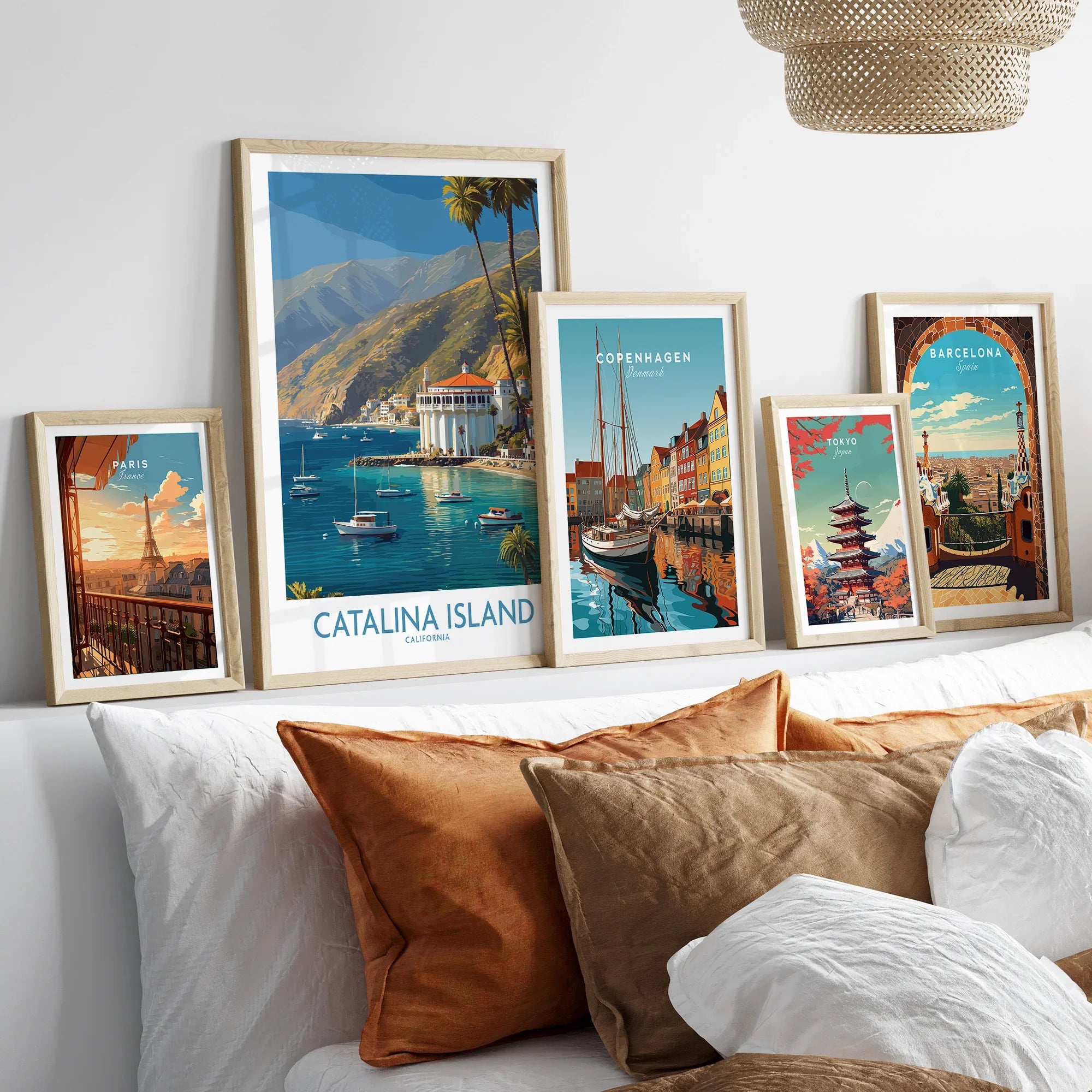 Framed travel poster art prints of Paris, Catalina Island, Copenhagen, Tokyo, and Barcelona above a bed