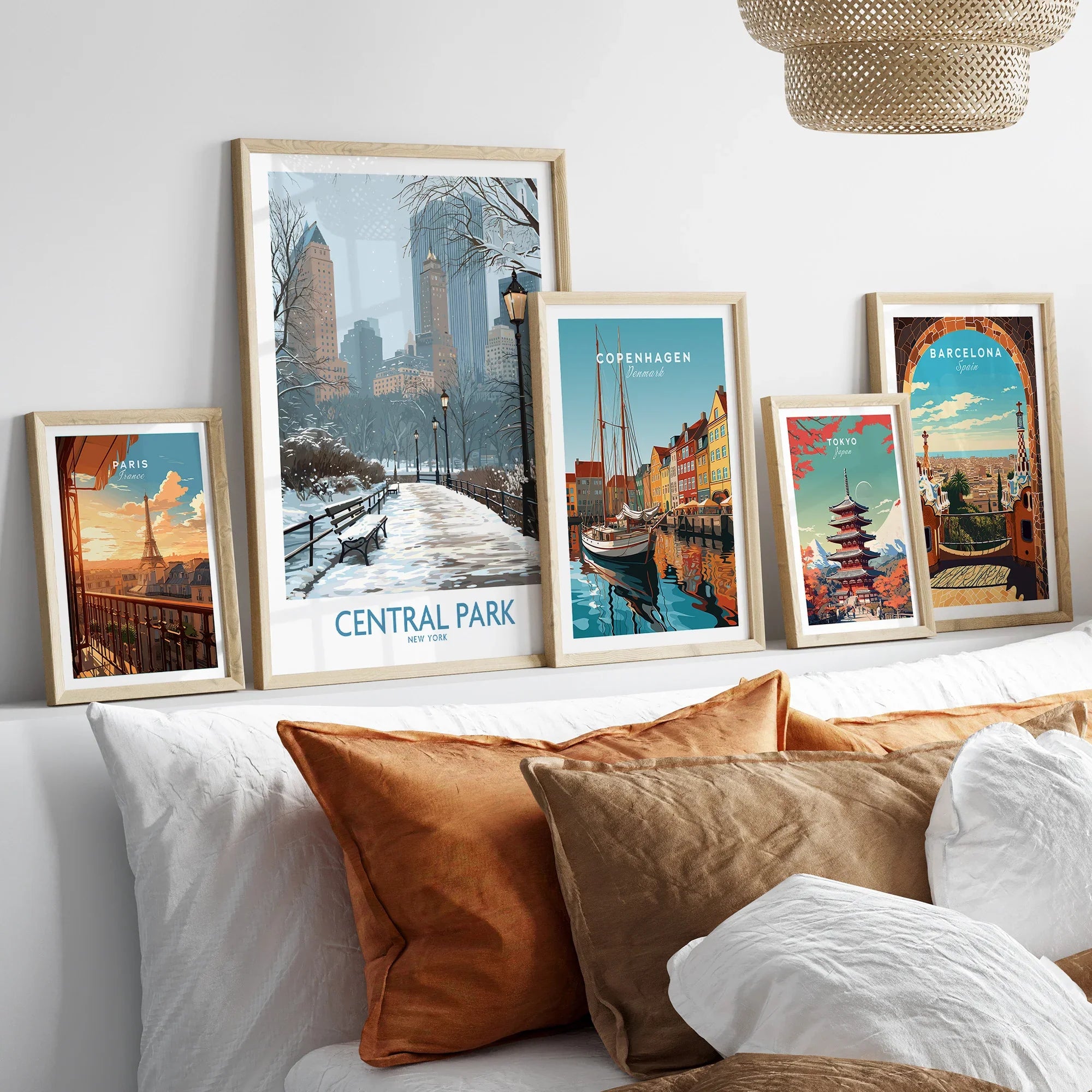 Travel city art prints in natural wood frames above a bed, featuring Central Park, Paris, Copenhagen, Tokyo, and Barcelona.