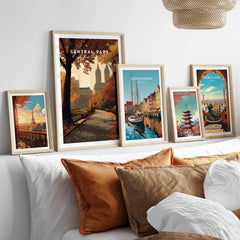 Framed travel posters of Paris, Central Park, Copenhagen, Tokyo, and Barcelona above a bed