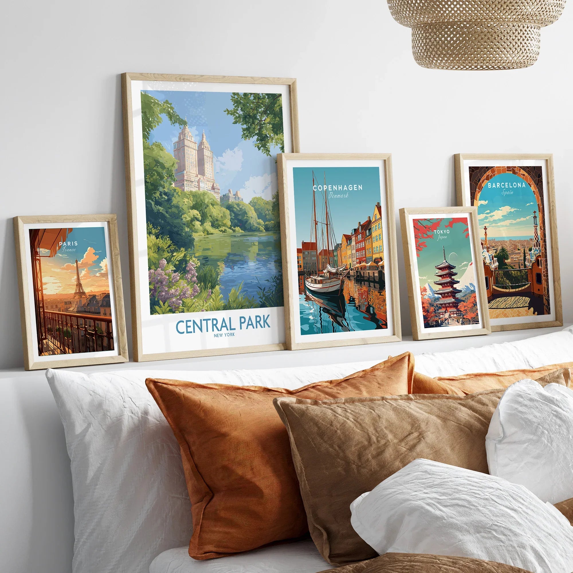 Travel posters set with Paris, Central Park, Copenhagen, Tokyo, and Barcelona in wood frames above bed