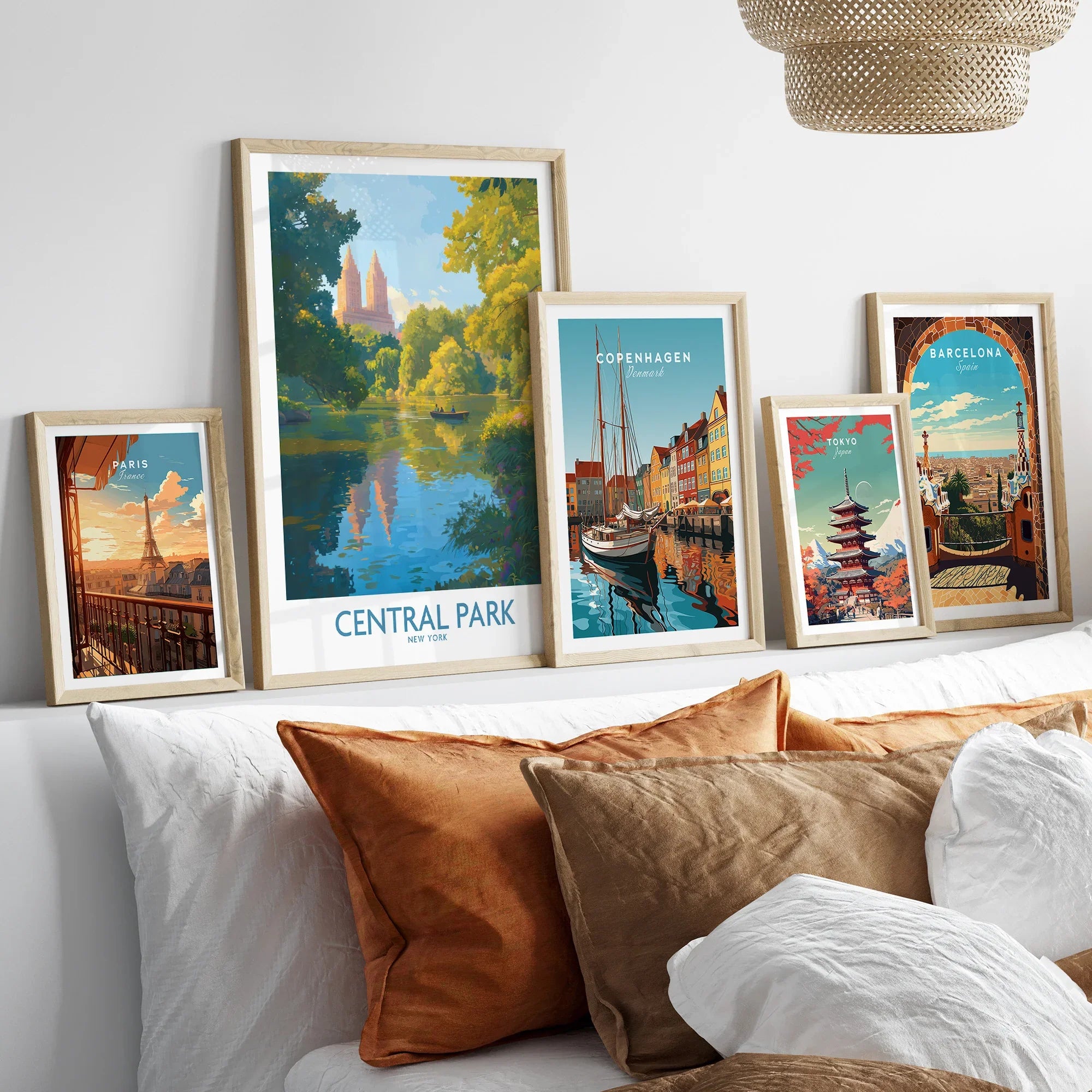 Set of five framed travel posters above bed, featuring city skylines and landmarks in natural wood frames.