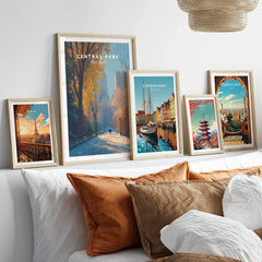 Framed travel art prints of Paris, Central Park, Copenhagen, Tokyo, and Barcelona above a bed.