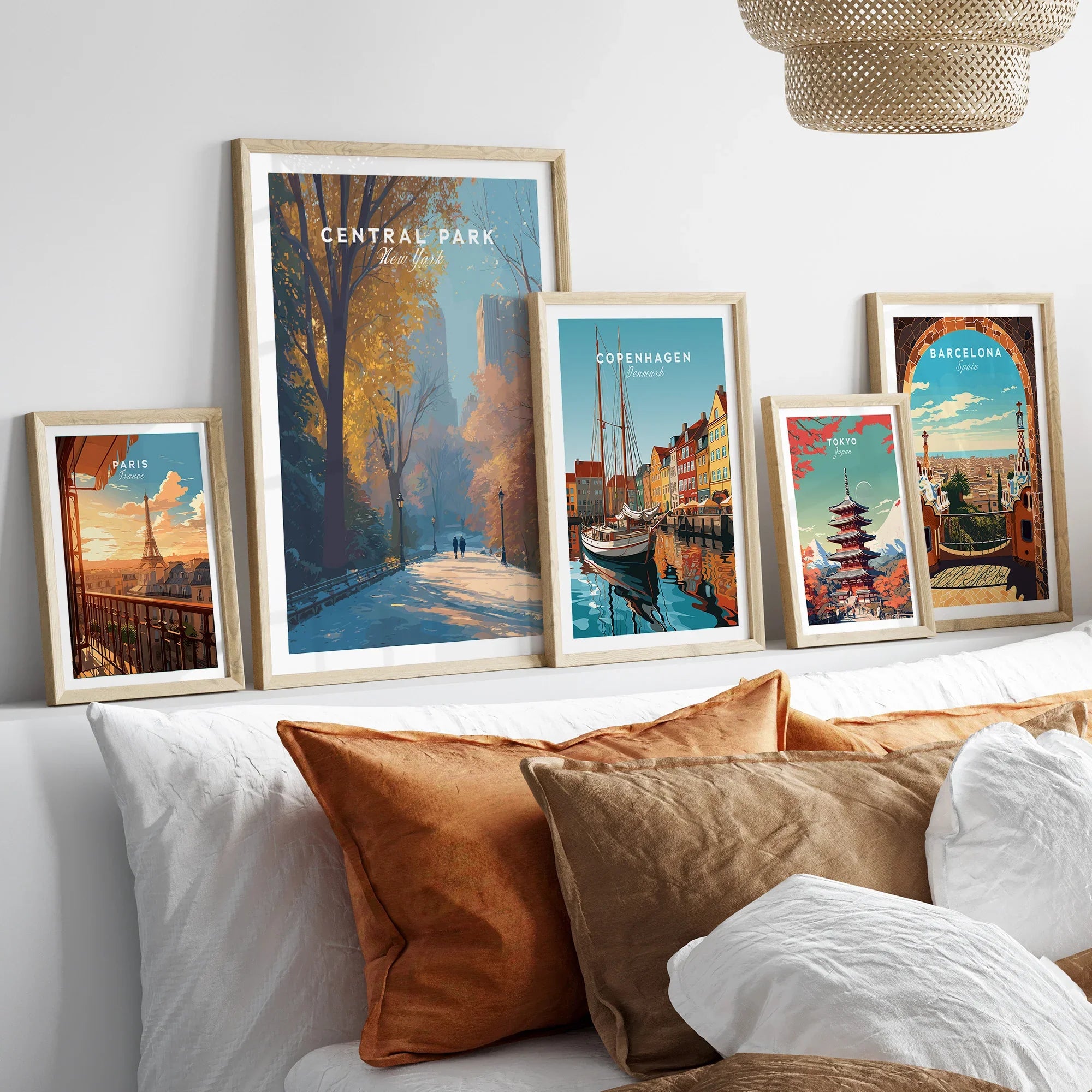 Framed travel art prints of Paris, Central Park, Copenhagen, Tokyo, and Barcelona above a bed.