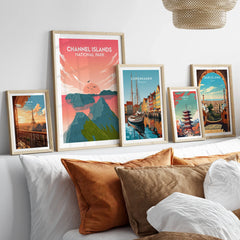 Framed travel art prints of Channel Islands, Paris, Copenhagen, Tokyo, and Barcelona above bed