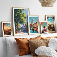 Set of five framed travel art prints above a bed, featuring Paris, Colchester, Copenhagen, Tokyo, and Barcelona.