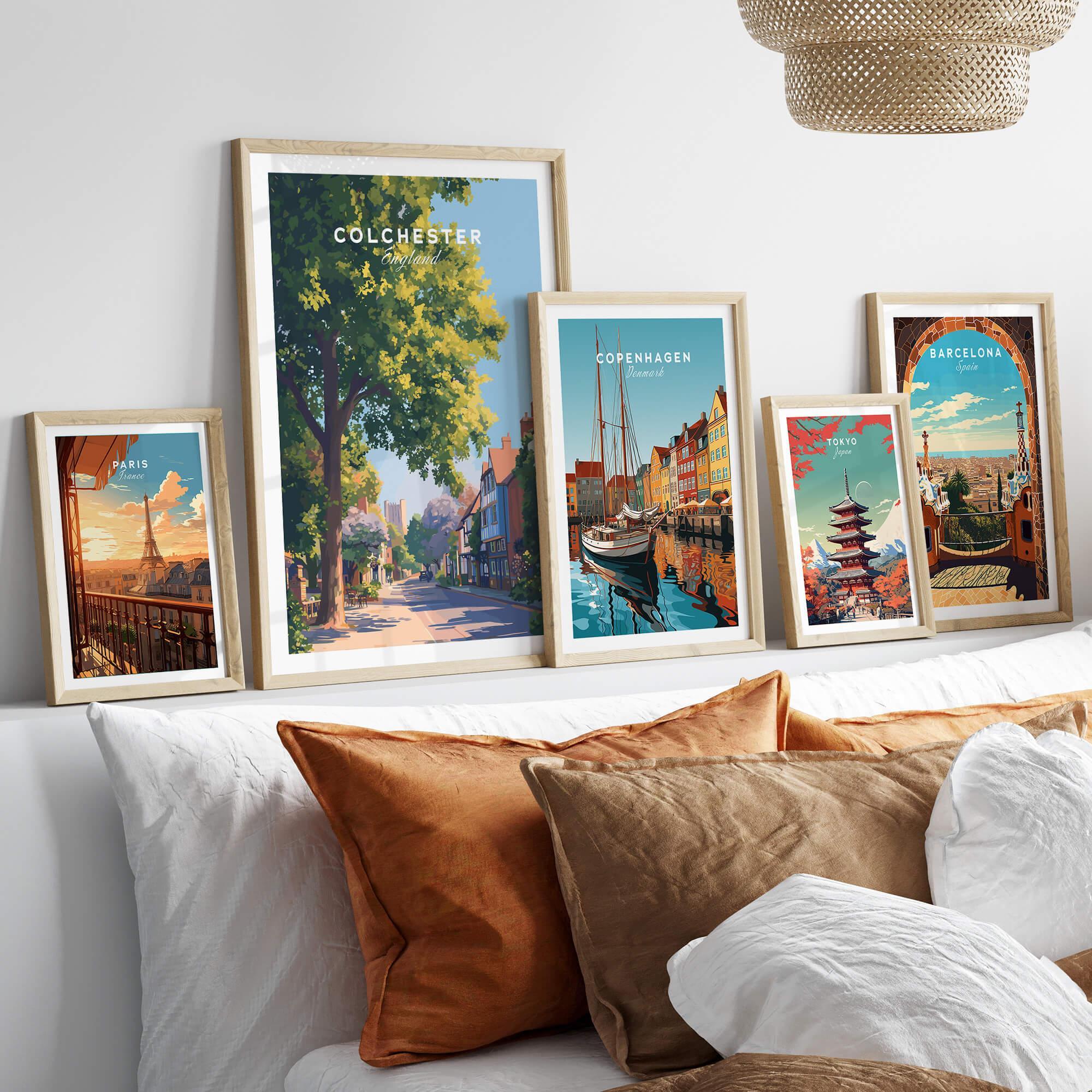 Set of five framed travel art prints above a bed, featuring Paris, Colchester, Copenhagen, Tokyo, and Barcelona.