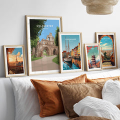 Framed travel posters of Colchester, Paris, Copenhagen, Tokyo, and Barcelona above a bed