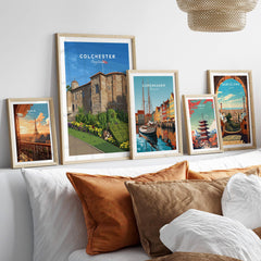 Set of five framed travel posters of Paris, Colchester, Copenhagen, Tokyo, and Barcelona above bed