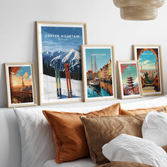 Copper Mountain Travel Poster – Colorado Mountain Summit & Ski Art Print displayed among other travel posters on a cozy couch.