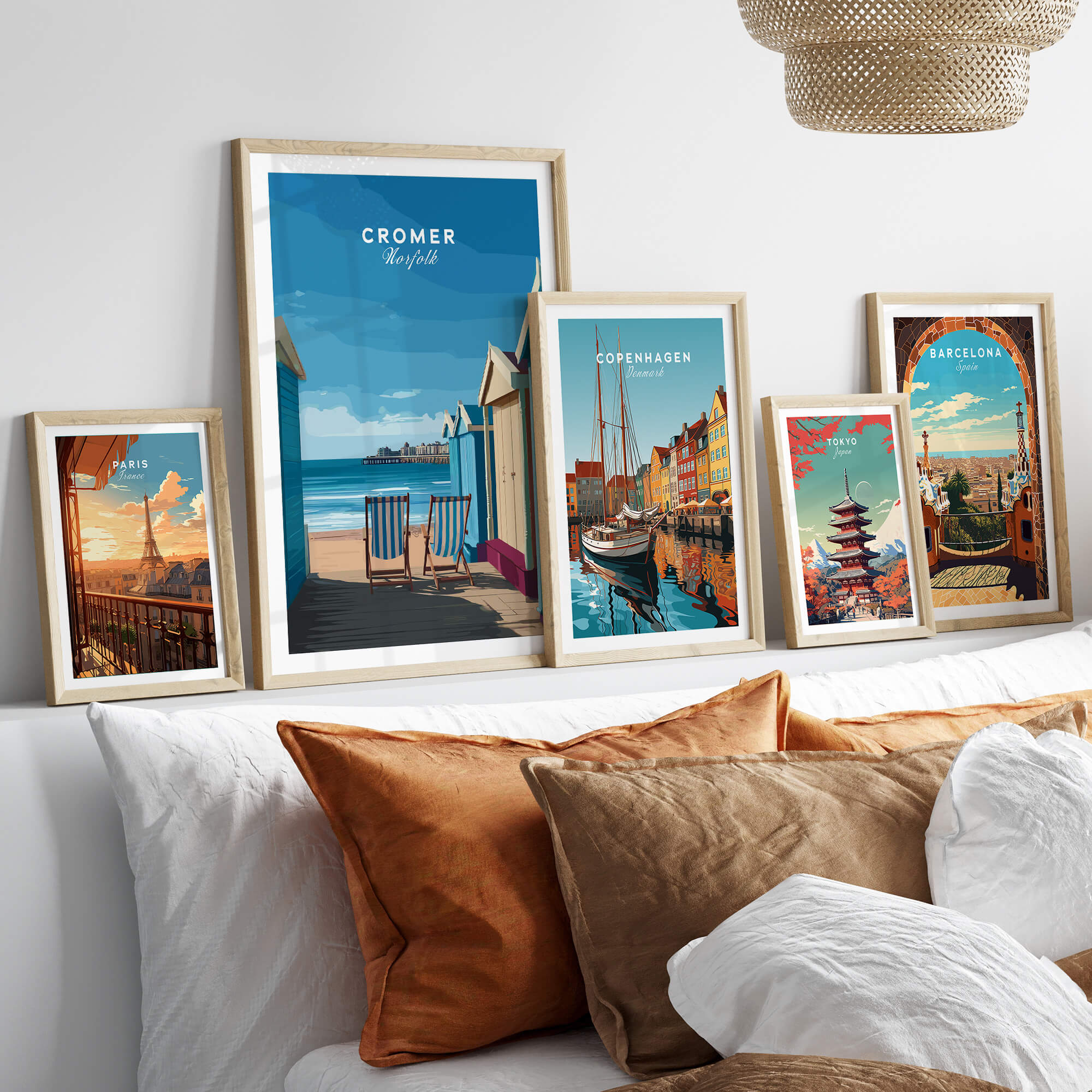 Cromer Travel Poster – Norfolk Beach Huts Art Print displayed in elegant frames on a stylish bed backdrop.