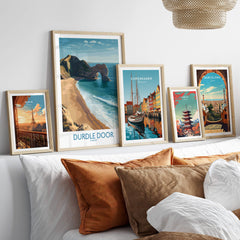 Durdle Door Art Print Dorset Wall Art displayed among other travel-themed art prints on a cozy sofa.