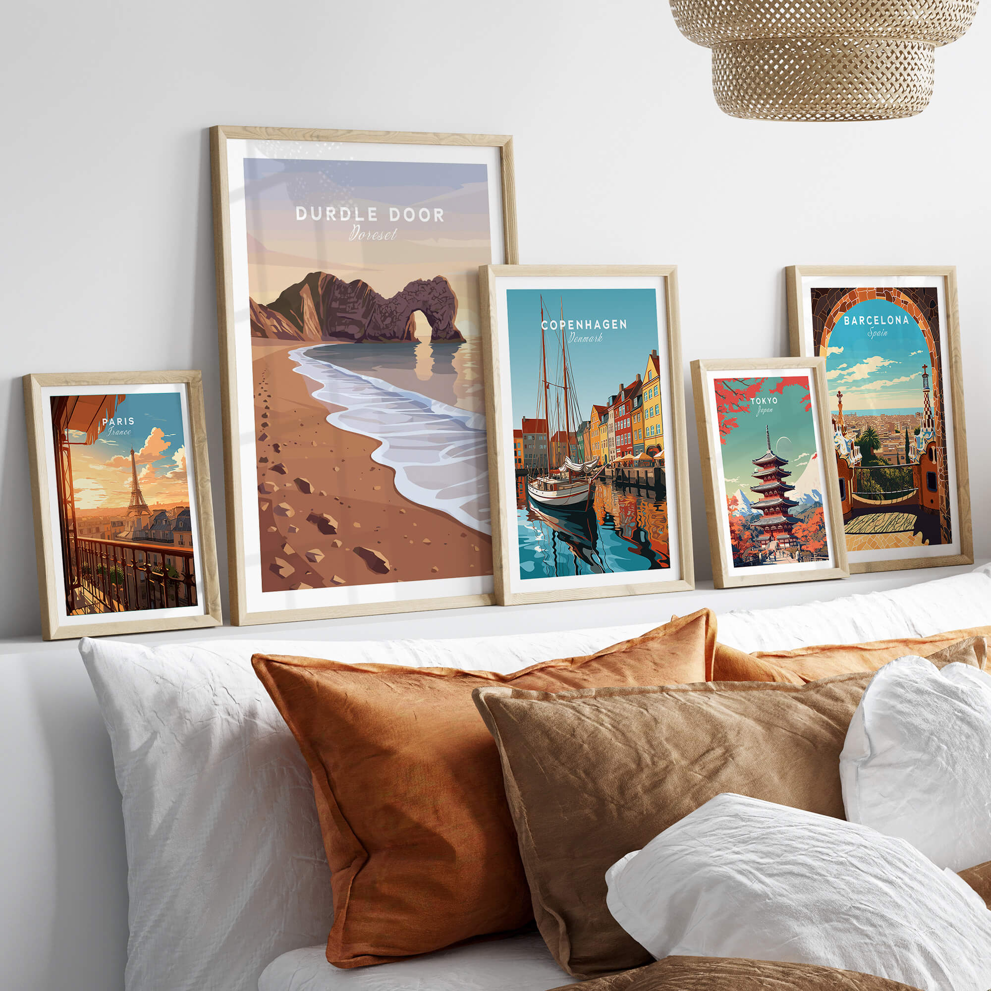 Durdle Door Travel Poster – Jurassic Coast Sunset Art displayed among other travel posters on a cozy sofa.