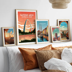 Framed travel and national park art prints above a bed with natural wood frames