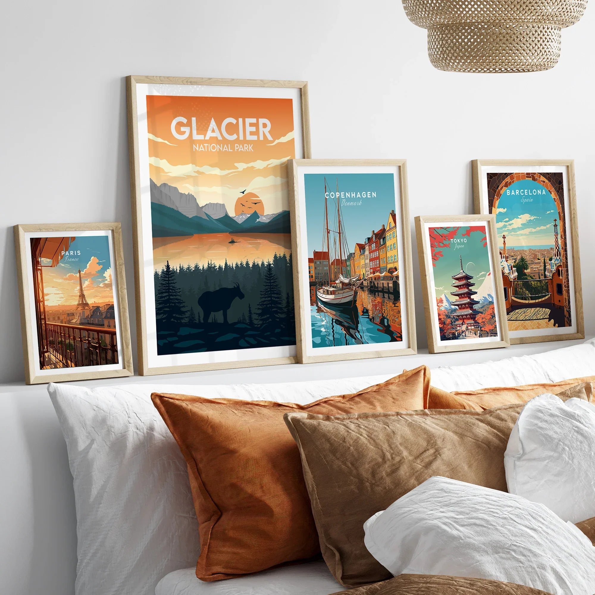 Set of five framed travel posters above bed, featuring Glacier National Park, Paris, Copenhagen, Tokyo, and Barcelona.