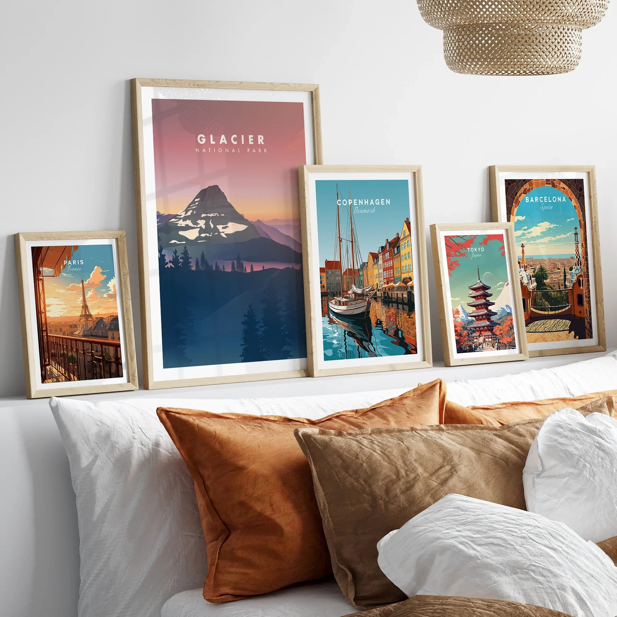 Travel art prints in natural wood frames above a bed, featuring Paris, Glacier National Park, Copenhagen, Tokyo, and Barcelona.