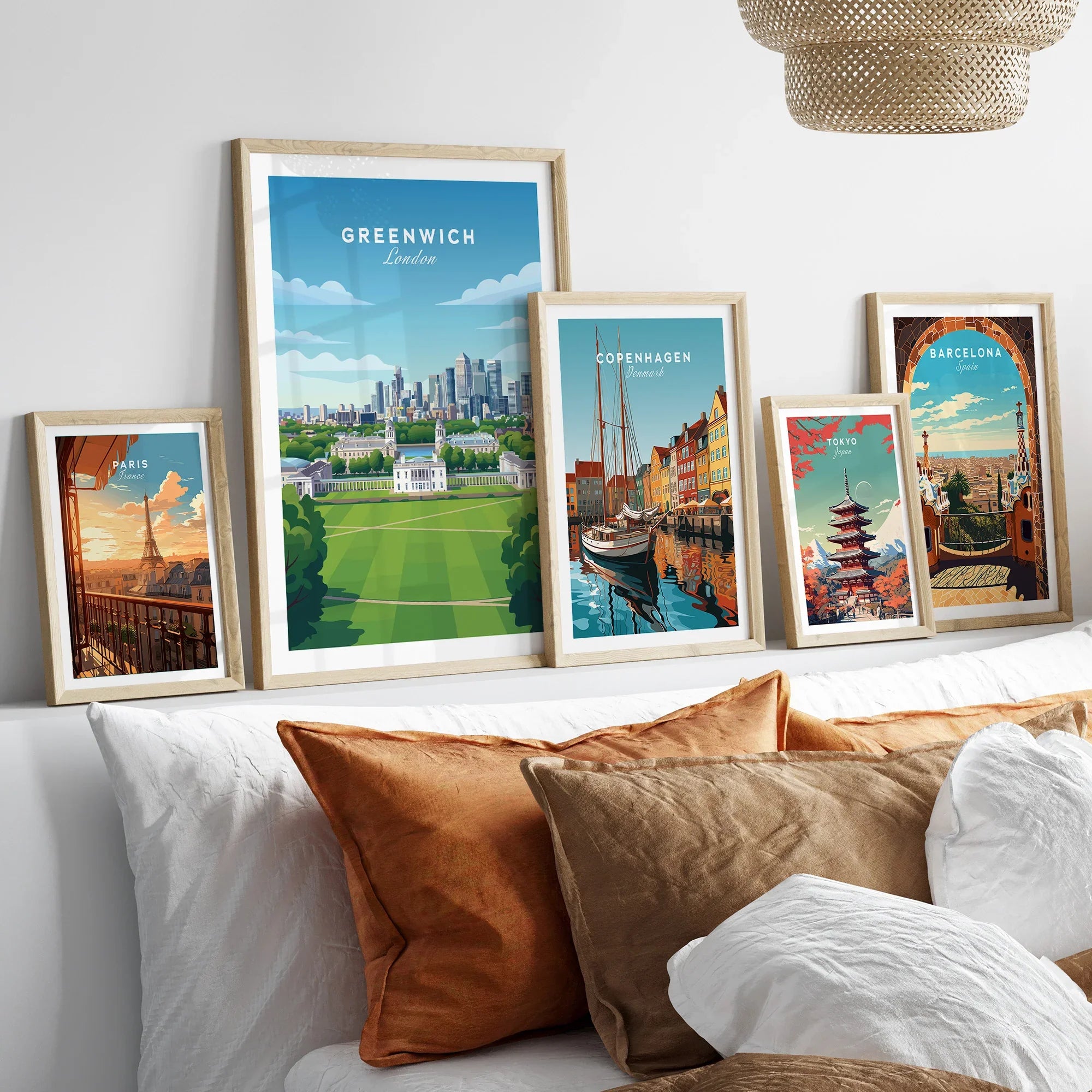 Set of five framed travel city posters including Greenwich, Copenhagen, Paris, Tokyo, Barcelona above a bed with natural wood frames.