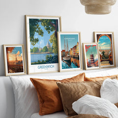 Set of five travel poster art prints in natural wood frames above a bed