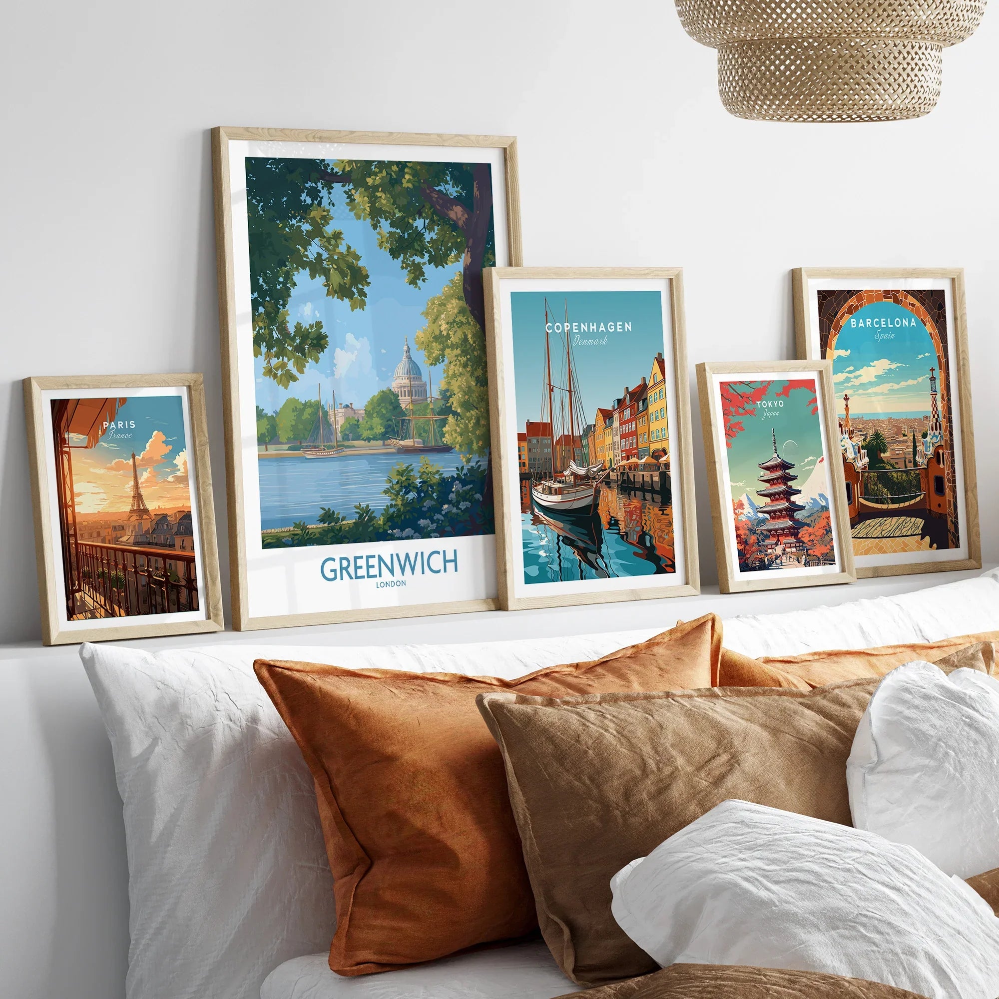 Set of five travel poster art prints in natural wood frames above a bed