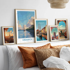 Travel poster art prints in natural wood frames displayed above bed in cozy bedroom decor