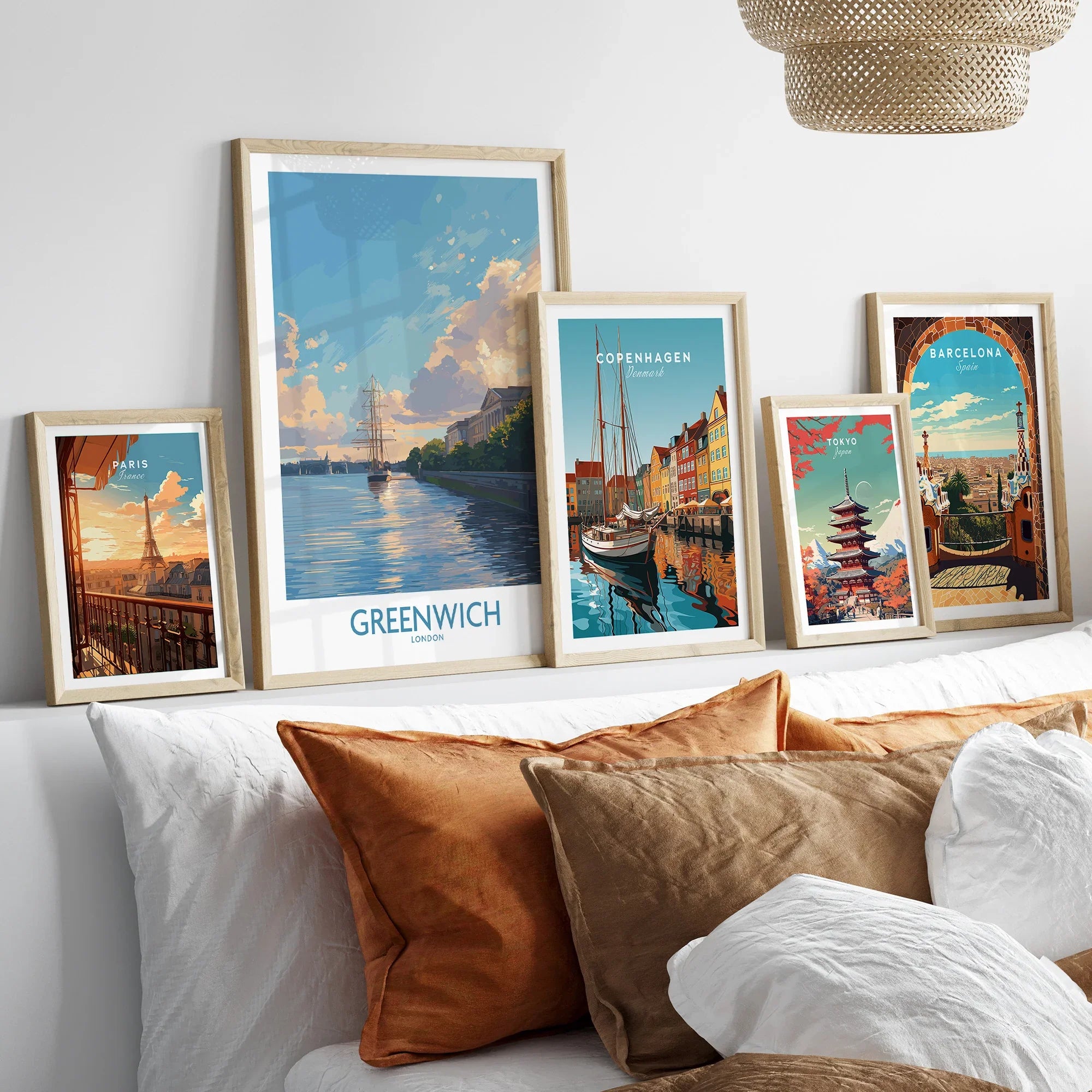 Travel poster art prints in natural wood frames displayed above bed in cozy bedroom decor