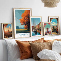 Set of five framed travel posters featuring world cities above a bed with earthy pillows