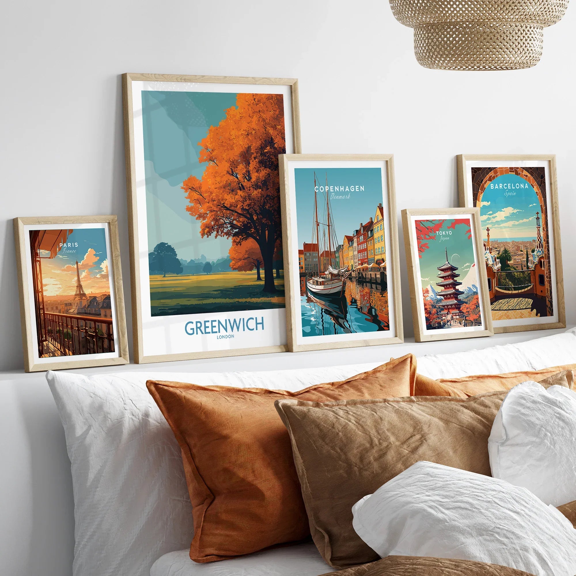 Set of five framed travel posters featuring world cities above a bed with earthy pillows