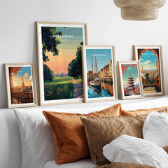 Framed travel posters of Greenwich, Paris, Copenhagen, Tokyo, and Barcelona above a bed